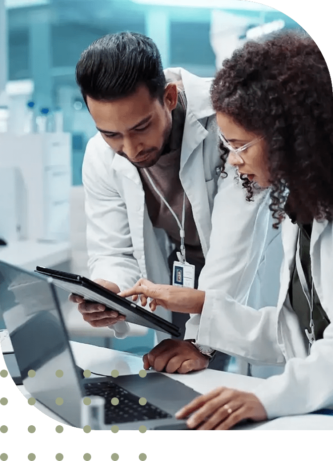 Two doctors reviewing medical data on a tablet in a clinical setting.