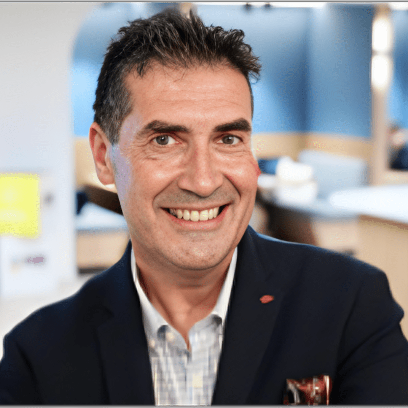 A smiling man in a navy blazer in an office setting.